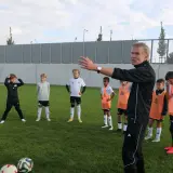 Trainer erklärt jungen Fußballern auf dem Feld Taktiken, die für ein DFB Duales Studium relevant sein könnten.