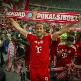 Harry Kane feiert mit seinen Teamkollegen und Fans einen Pokalsieg. Die Spieler halten ein Banner mit der Aufschrift "Rekord Pokalsiege".