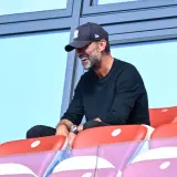 Jürgen Klopp, mit einer New York Yankees Kappe, lacht auf der Tribüne. Vielleicht beobachtet er ein Spiel des DFB.