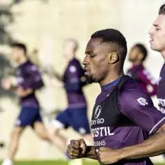 Fußballer im Trainingsanzug machen einen Shuffle Run auf dem Feld.