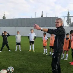 Trainer erklärt jungen Fußballern auf dem Feld Taktiken, die für ein DFB Duales Studium relevant sein könnten.