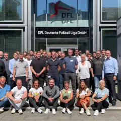Eine Gruppe von Mitarbeitern der DFL vor dem Gebäude. Sie besprechen ihre Mannschaftsrat Aufgaben.
