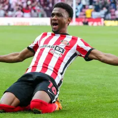 Amad Diallo feiert jubelnd auf dem Rasen, die Arme ausgebreitet, in seinem rot-weißen Trikot.