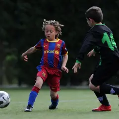 Ein junger Fußballer, vielleicht ein **Xavi Simons Kind**, dribbelt im Barcelona-Trikot auf dem Feld.