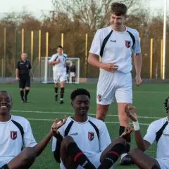 Junge Fußballer in weißen Trikots meditieren auf dem Feld. Ein Scout beobachtet sie aufmerksam.