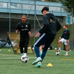 Trainer leitet den Aufbau Training auf dem Fußballplatz. Junge Spieler üben mit dem Ball.
