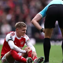 Martin Ødegaard sitzt verletzt auf dem Rasen, während ein Schiedsrichter ihn beobachtet.