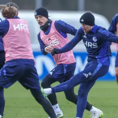 Fußballer im Jugendtraining üben auf dem Rasen. Ein Spieler schießt den Ball, während andere ihn beobachten.