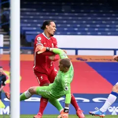 Van Dijk hält den Torwart fest, während ein Spieler von Everton im Hintergrund steht.
