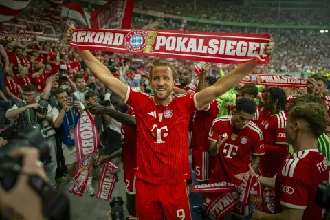 Harry Kane feiert mit seinen Teamkollegen und Fans einen Pokalsieg. Die Spieler halten ein Banner mit der Aufschrift "Rekord Pokalsiege".