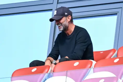 Jürgen Klopp, mit einer New York Yankees Kappe, lacht auf der Tribüne. Vielleicht beobachtet er ein Spiel des DFB.