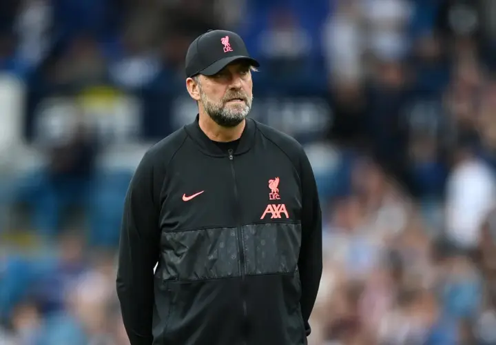 Trainer Klopp, mit Bart und Kappe, blickt nachdenklich. Er trägt eine schwarze Jacke mit dem Liverpool-Logo.