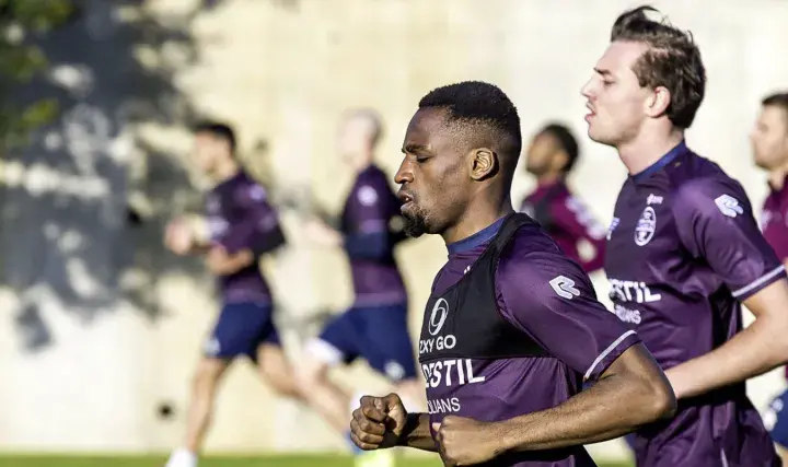 Fußballer im Trainingsanzug machen einen Shuffle Run auf dem Feld.