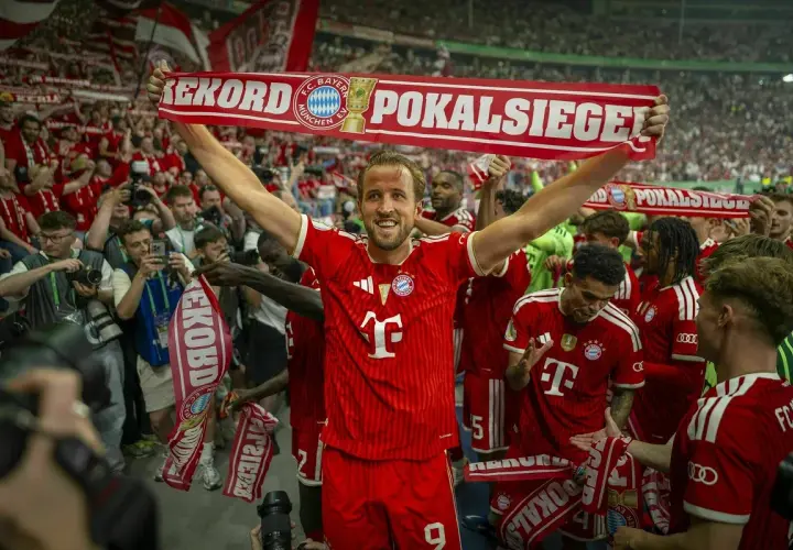 Harry Kane feiert mit seinen Teamkollegen und Fans einen Pokalsieg. Die Spieler halten ein Banner mit der Aufschrift "Rekord Pokalsiege".