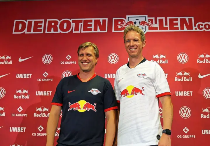 Julian Nagelsmann und ein Kollege posieren vor der roten Kulisse von RB Leipzig.