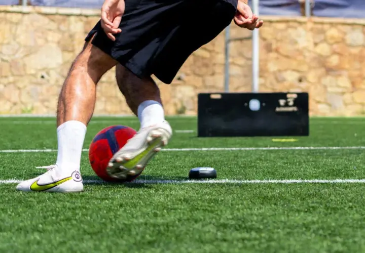 Fußballer trainiert seine reaktionsschnelligkeit mit einem Ball und einem kleinen Trainingsgerät auf Kunstrasen.