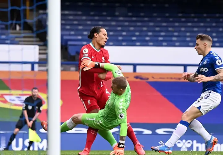 Van Dijk hält den Torwart fest, während ein Spieler von Everton im Hintergrund steht.