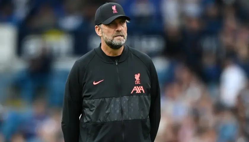 Trainer Klopp, mit Bart und Kappe, blickt nachdenklich. Er trägt eine schwarze Jacke mit dem Liverpool-Logo.