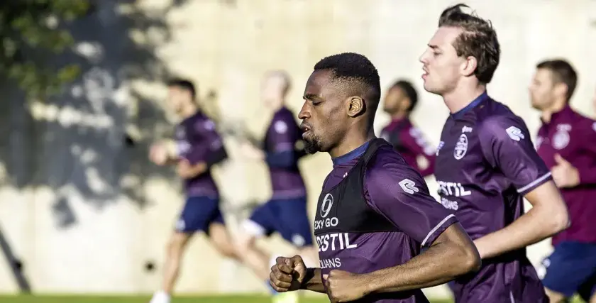 Fußballer im Trainingsanzug machen einen Shuffle Run auf dem Feld.