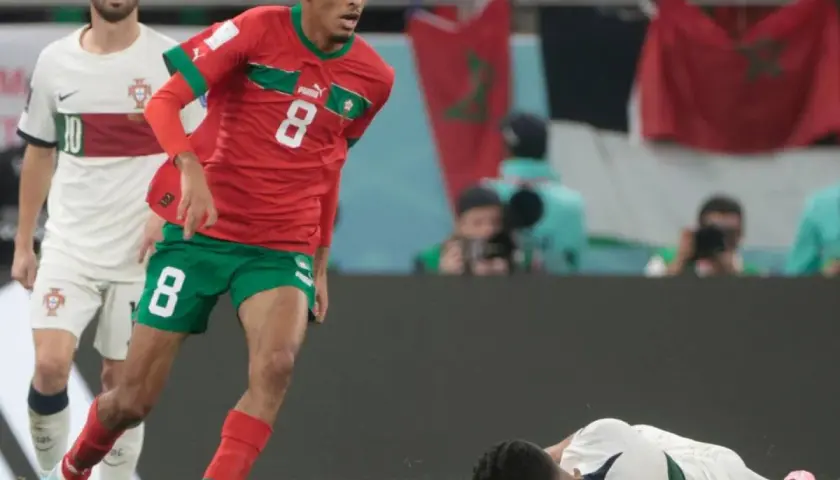 Azzedine Ounahi im roten Trikot mit der Nummer 8 dribbelt, während ein portugiesischer Spieler im Hintergrund steht.