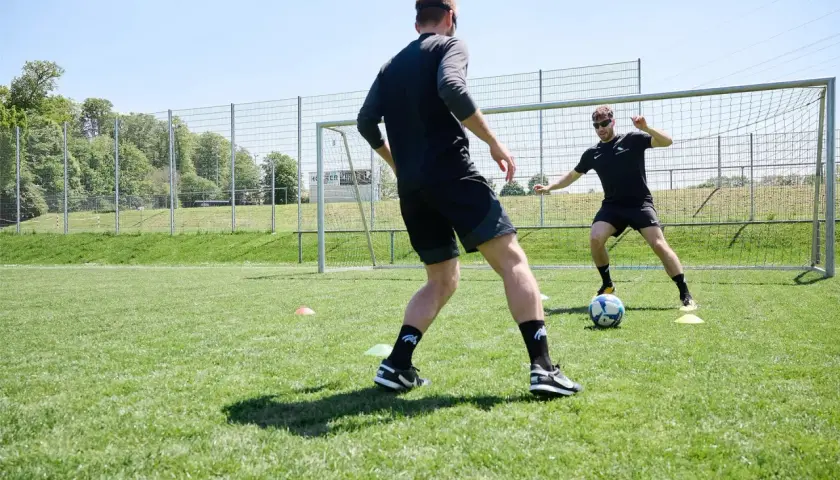 Zwei Fußballer trainieren auf einem Rasenplatz. Der Fokus liegt auf dem neurozentrierten Training, um Koordination und Reaktionsfähigkeit zu verbessern.