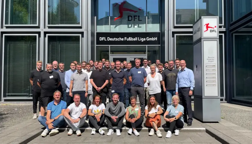 Eine Gruppe von Mitarbeitern der DFL vor dem Gebäude. Sie besprechen ihre Mannschaftsrat Aufgaben.