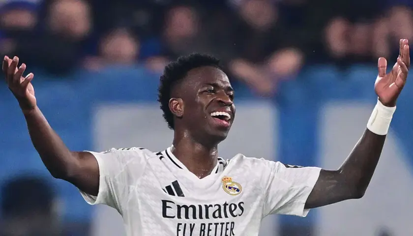 Vinícius Júnior jubelt ausgelassen im weißen Trikot von Real Madrid, die Arme erhoben.
