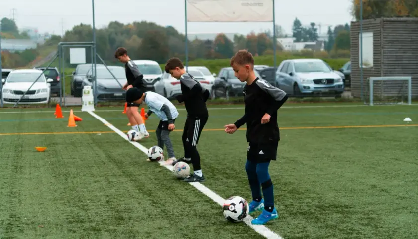 Jungs beim Kinderfußball Training üben mit Bällen auf dem Kunstrasen.
