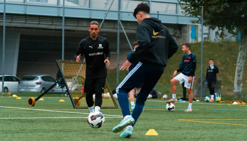Trainer leitet den Aufbau Training auf dem Fußballplatz. Junge Spieler üben mit dem Ball.
