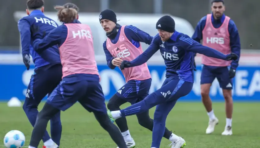 Fußballer im Jugendtraining üben auf dem Rasen. Ein Spieler schießt den Ball, während andere ihn beobachten.