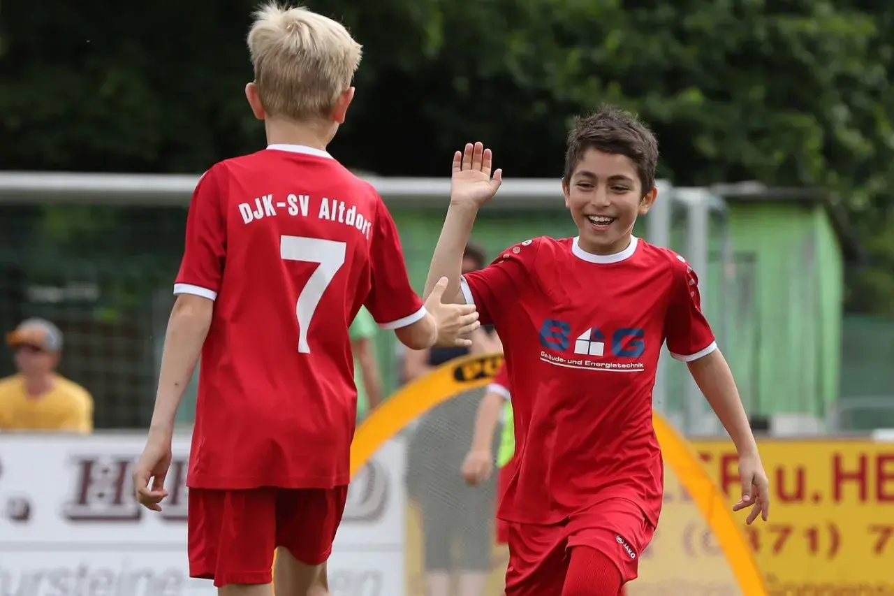 Zwei jubelnde Jungen in roten Fußballtrikots geben sich die Hand. Ein toller Moment der Jugend Spielzeit.