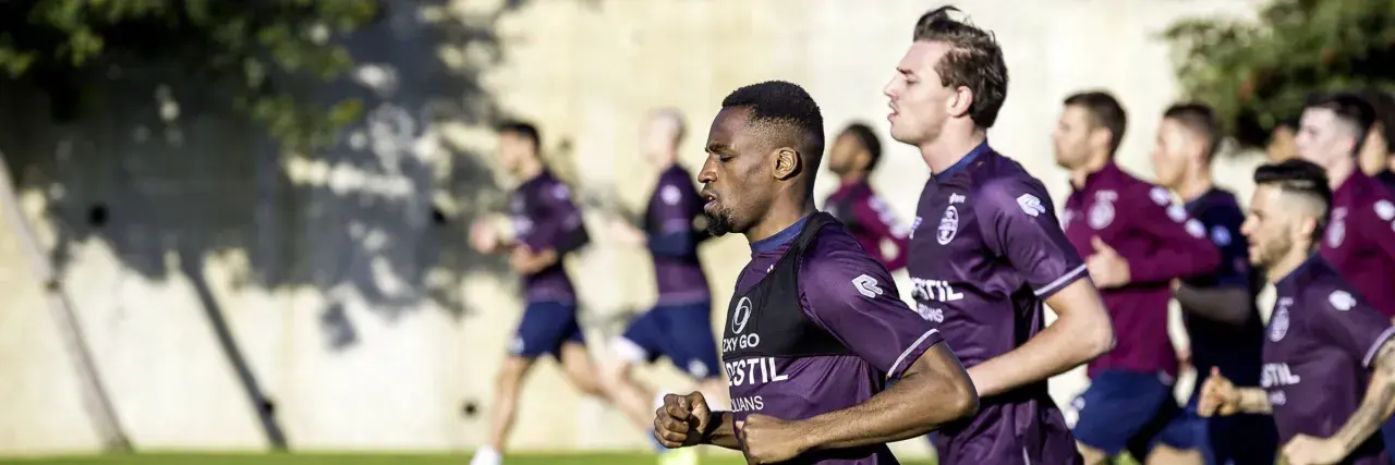 Fußballer im Trainingsanzug machen einen Shuffle Run auf dem Feld.