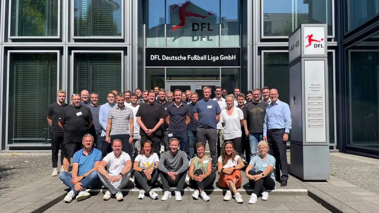 Eine Gruppe von Mitarbeitern der DFL vor dem Gebäude. Sie besprechen ihre Mannschaftsrat Aufgaben.