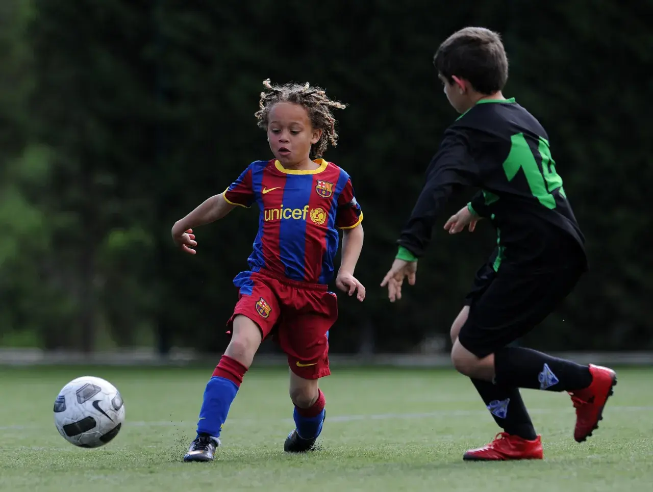 Ein junger Fußballer, vielleicht ein **Xavi Simons Kind**, dribbelt im Barcelona-Trikot auf dem Feld.