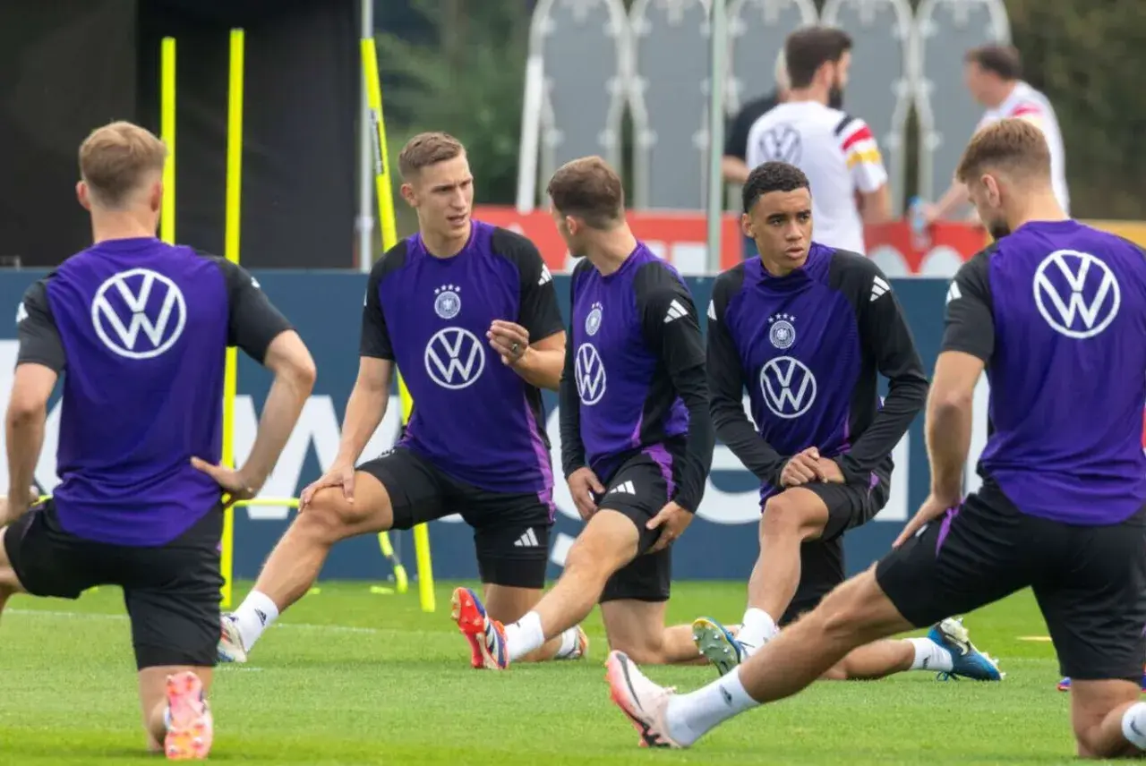 Fußballer in violetten Trikots dehnen ihre Wade auf dem Trainingsplatz.