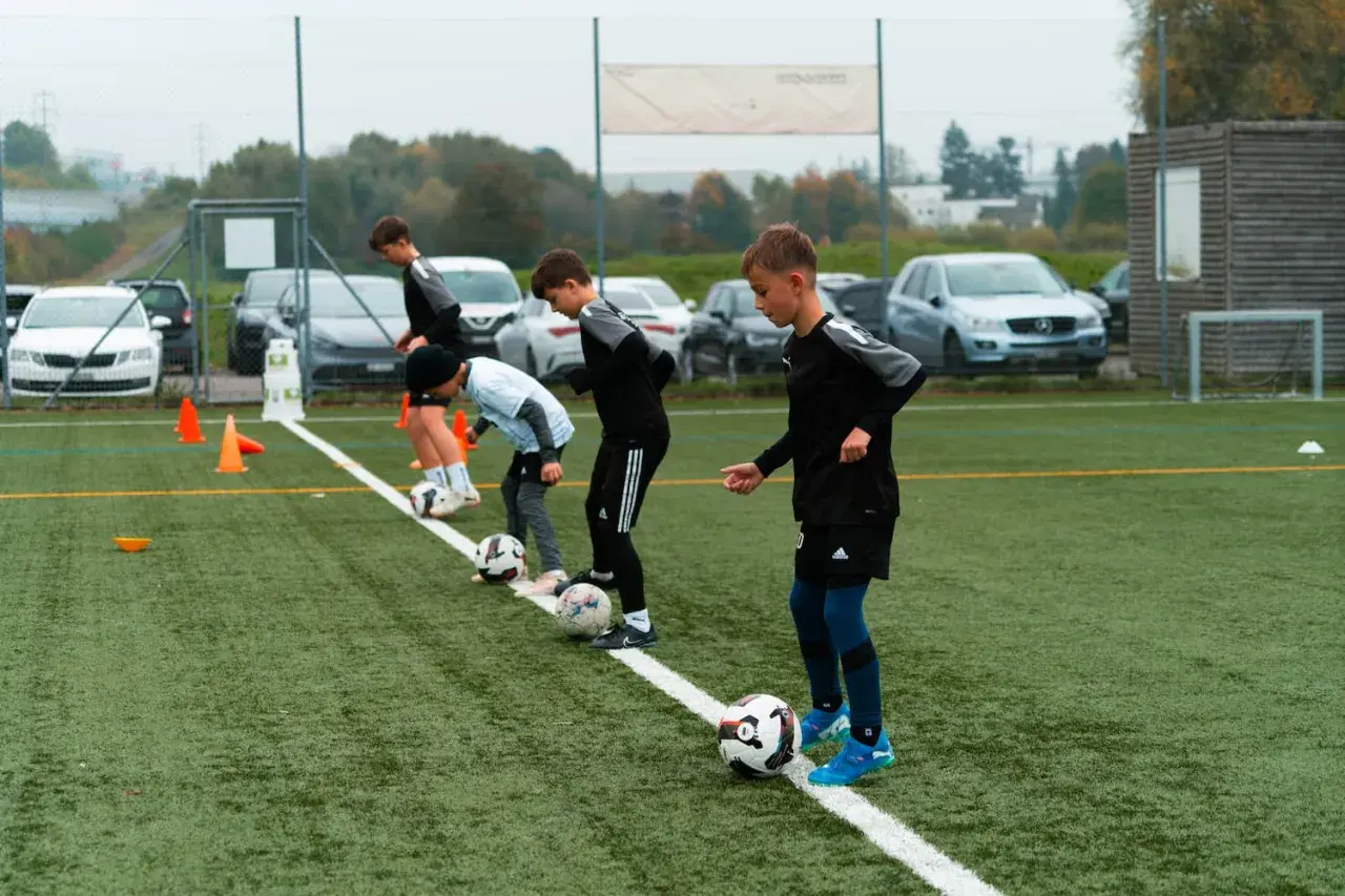 Jungs beim Kinderfußball Training üben mit Bällen auf dem Kunstrasen.
