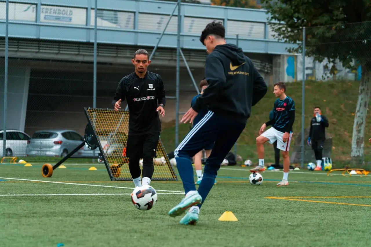 Trainer leitet den Aufbau Training auf dem Fußballplatz. Junge Spieler üben mit dem Ball.