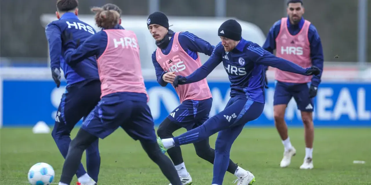 Fußballer im Jugendtraining üben auf dem Rasen. Ein Spieler schießt den Ball, während andere ihn beobachten.