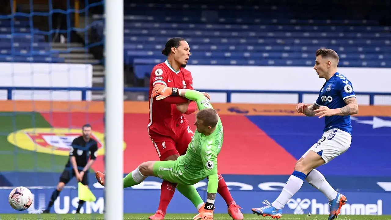 Van Dijk hält den Torwart fest, während ein Spieler von Everton im Hintergrund steht.