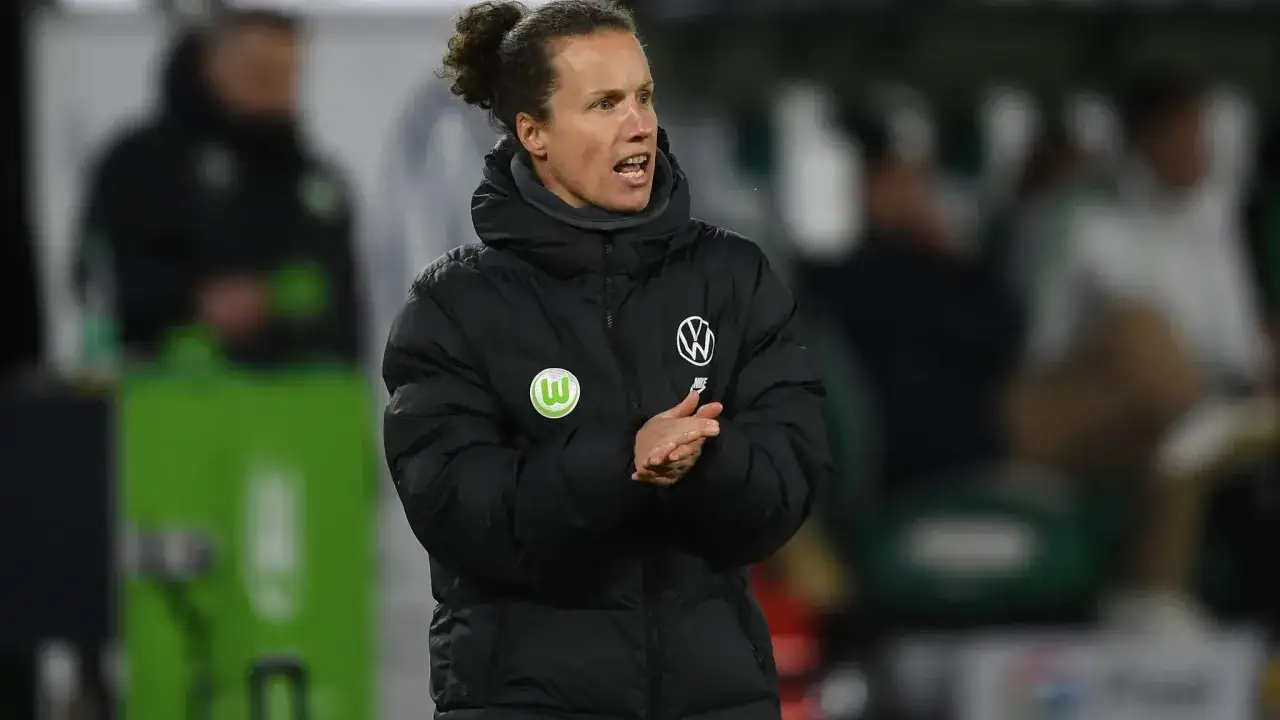 Tommy Stroot, Trainer des VfL Wolfsburg, gestikuliert aufmunternd in seiner Winterjacke.