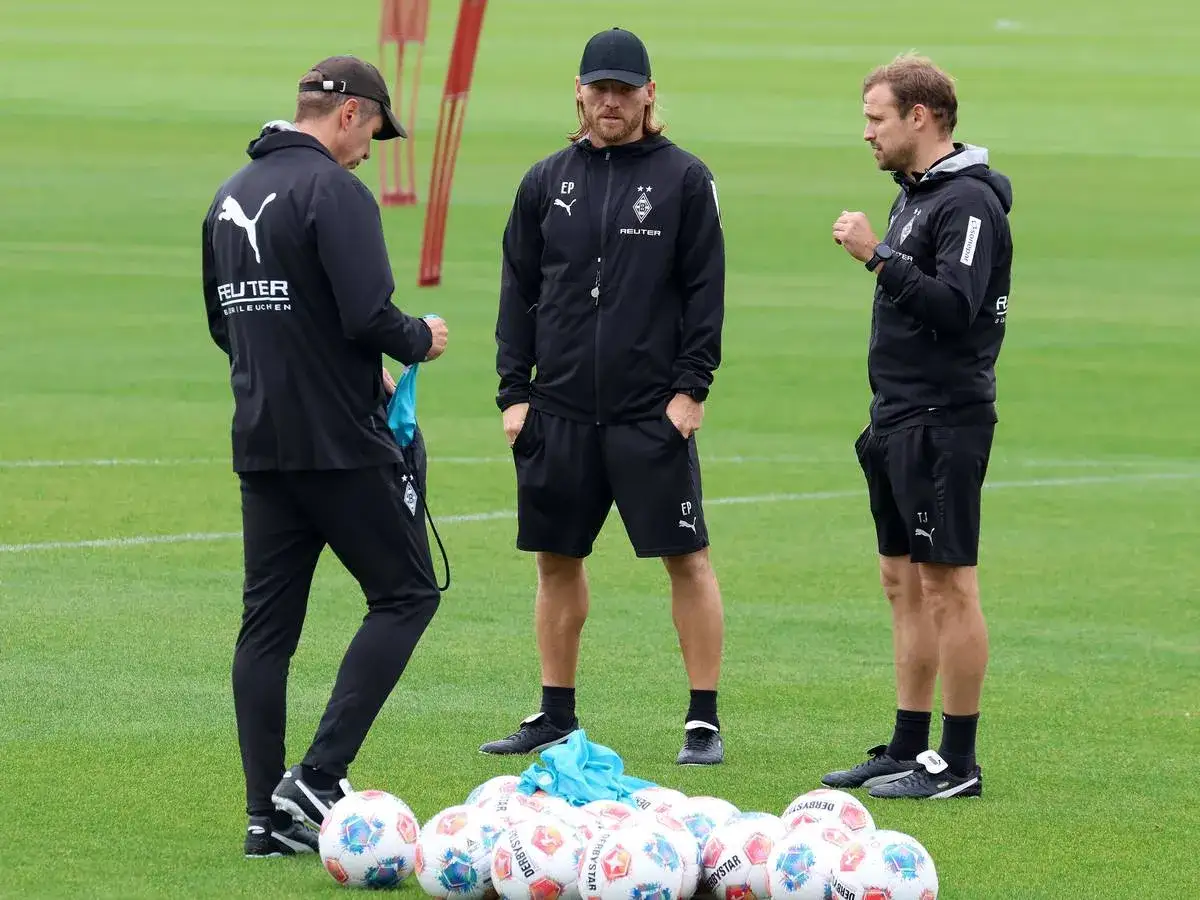 Drei Trainer auf dem Rasen, umgeben von Fu&szlig;b&auml;llen. Vielleicht planen sie die n&auml;chsten Schritte f&uuml;r Roberto Carlos' bisherige Trainerstationen.