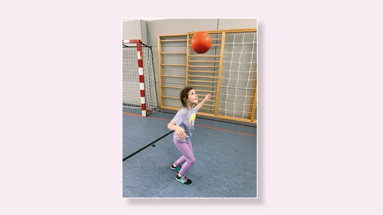 Ein M&auml;dchen &uuml;bt den Kopfball in der Turnhalle.
