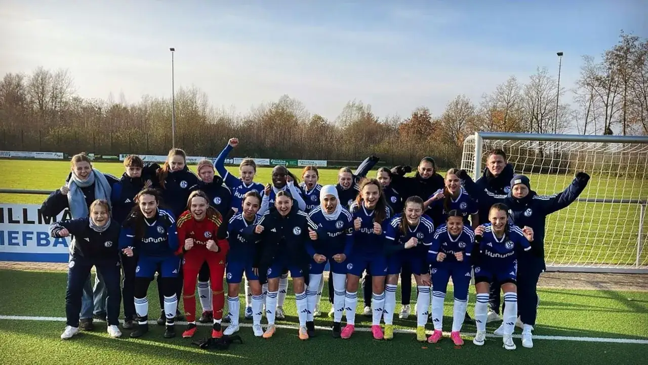 Jubelnde u17 Juniorinnen des FC Schalke 04 posieren nach einem Sieg vor dem Tor.