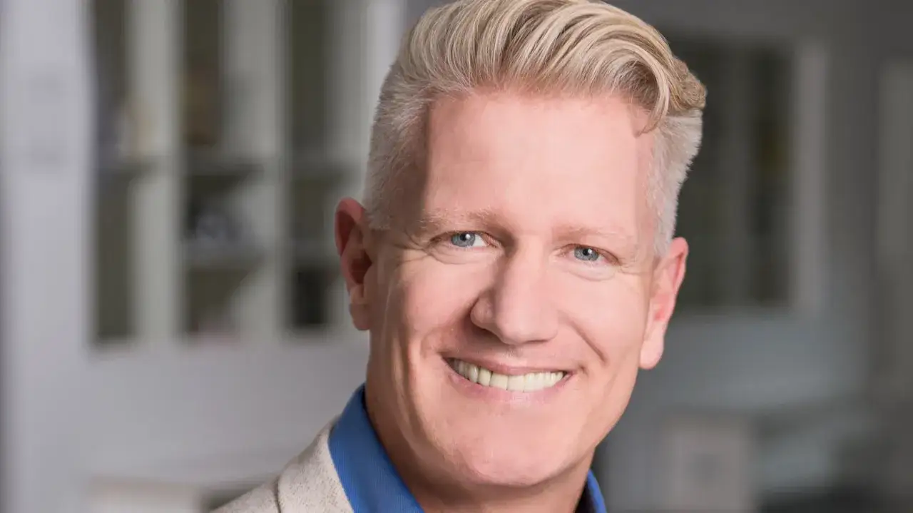 Ein Mann mit blonden Haaren und blauen Augen l&auml;chelt. Er k&ouml;nnte ein Sportpsychologe sein, der Athleten hilft, ihre mentale St&auml;rke zu entwickeln.
