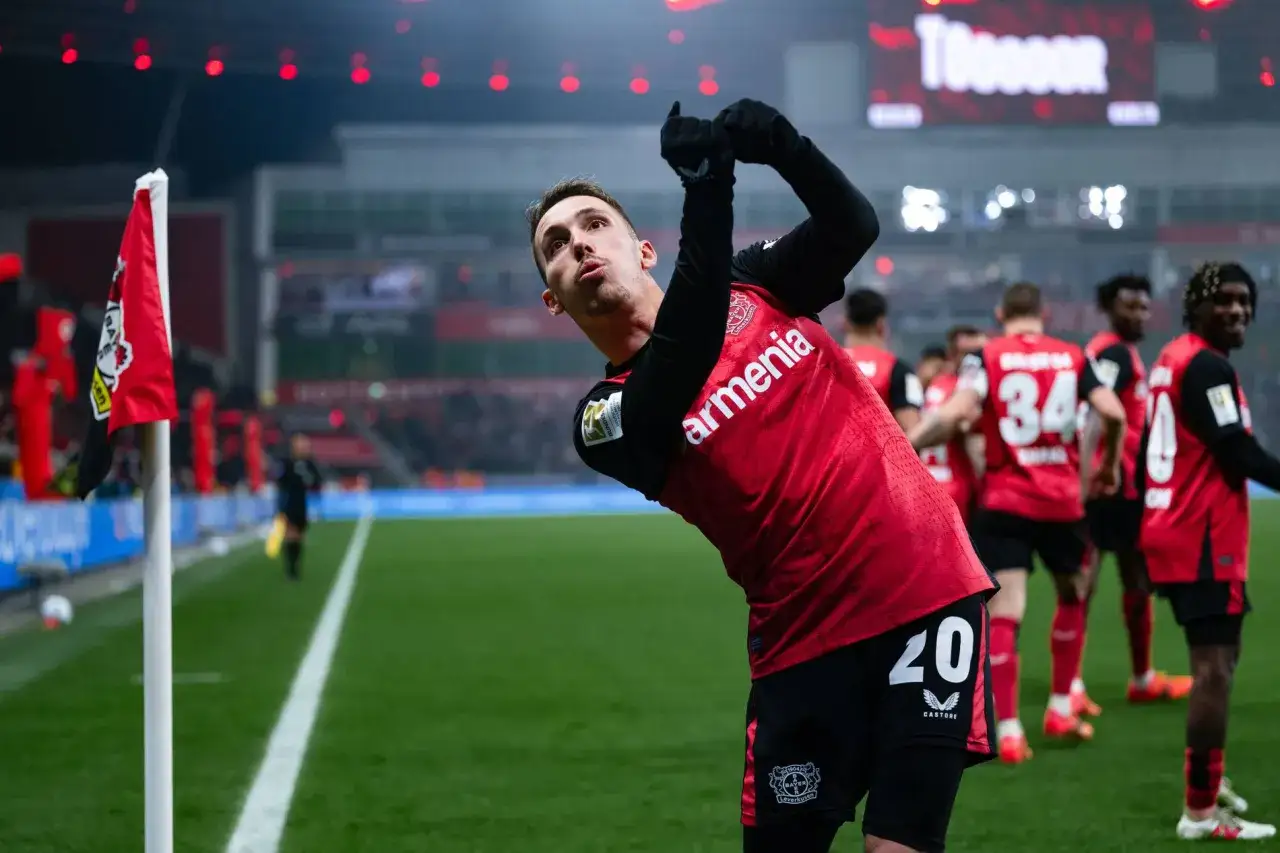 Alejandro Grimaldo jubelt nach einem Tor, seine Arme sind erhoben. Im Hintergrund stehen seine Mitspieler.
